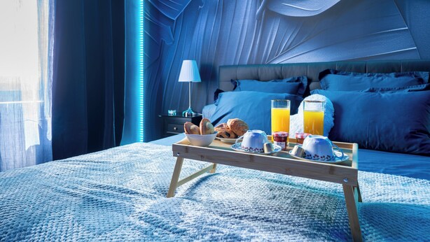 A bedroom with a bed, bedside table, and a tray with breakfast items. - Luxuria Love Room Avignon (Avignon)