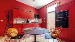 A modern kitchen with red cabinetry, a round dining table, and two chairs. - Luxuria Love Room Avignon (Avignon)