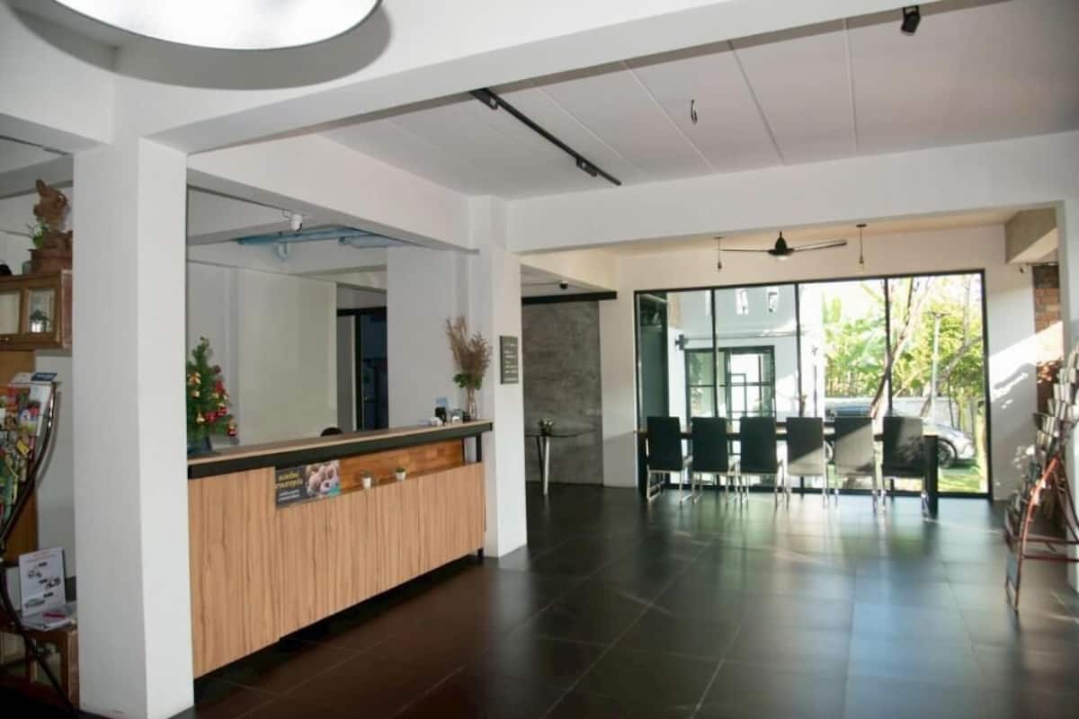 A reception area with a wooden counter, a large mirror, and a seating area with chairs and a table.