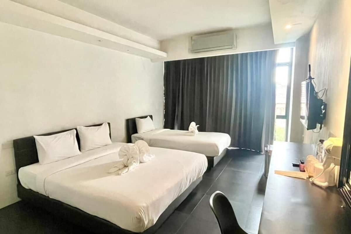 A hotel room with two beds, a desk, and a chair.