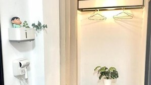 A modern bathroom with a black countertop, a hairdryer, a small shelf with a plant, and a wall-mounted drying rack. - AZZ Hotel (Chiang Mai)