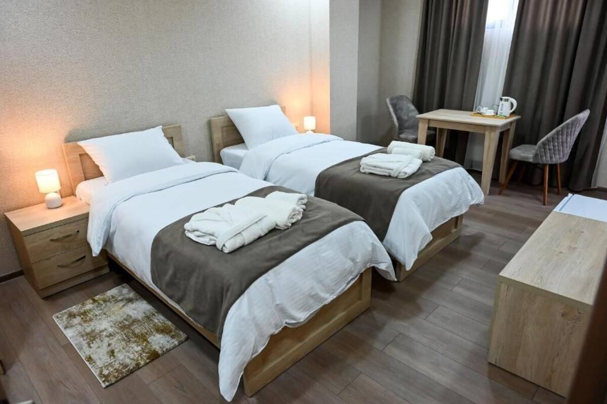 Una habitación de hotel con dos camas, un escritorio, una silla y una alfombra pequeña.