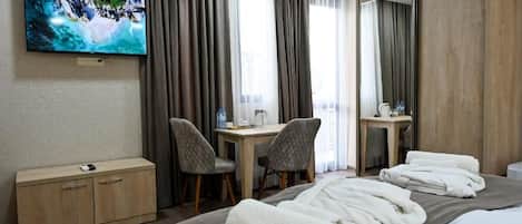Habitación de hotel con cama, escritorio, dos sillas, televisor, armario y espejo.