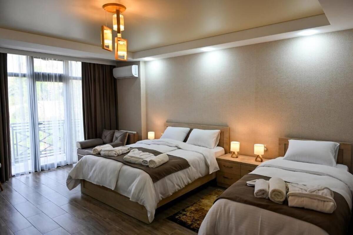 Habitación de hotel con dos camas, un sofá y un balcón.