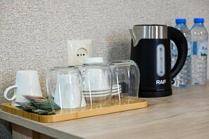 Eine Küchenarbeitsplatte mit Kaffeemaschine, Wasserkocher und Tablett mit Tassen und Tellern.