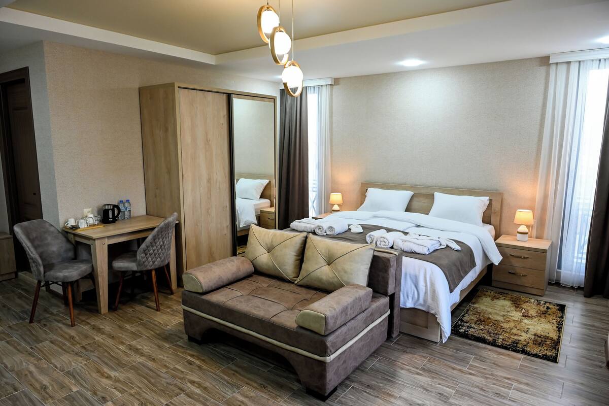 Una habitación de hotel con cama, sofá, escritorio y silla.