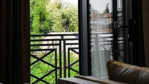 Ein Hotelzimmer mit einer großen Schiebeglasdoor zu einem Balkon mit Blick auf Grünflächen und Gebäude.