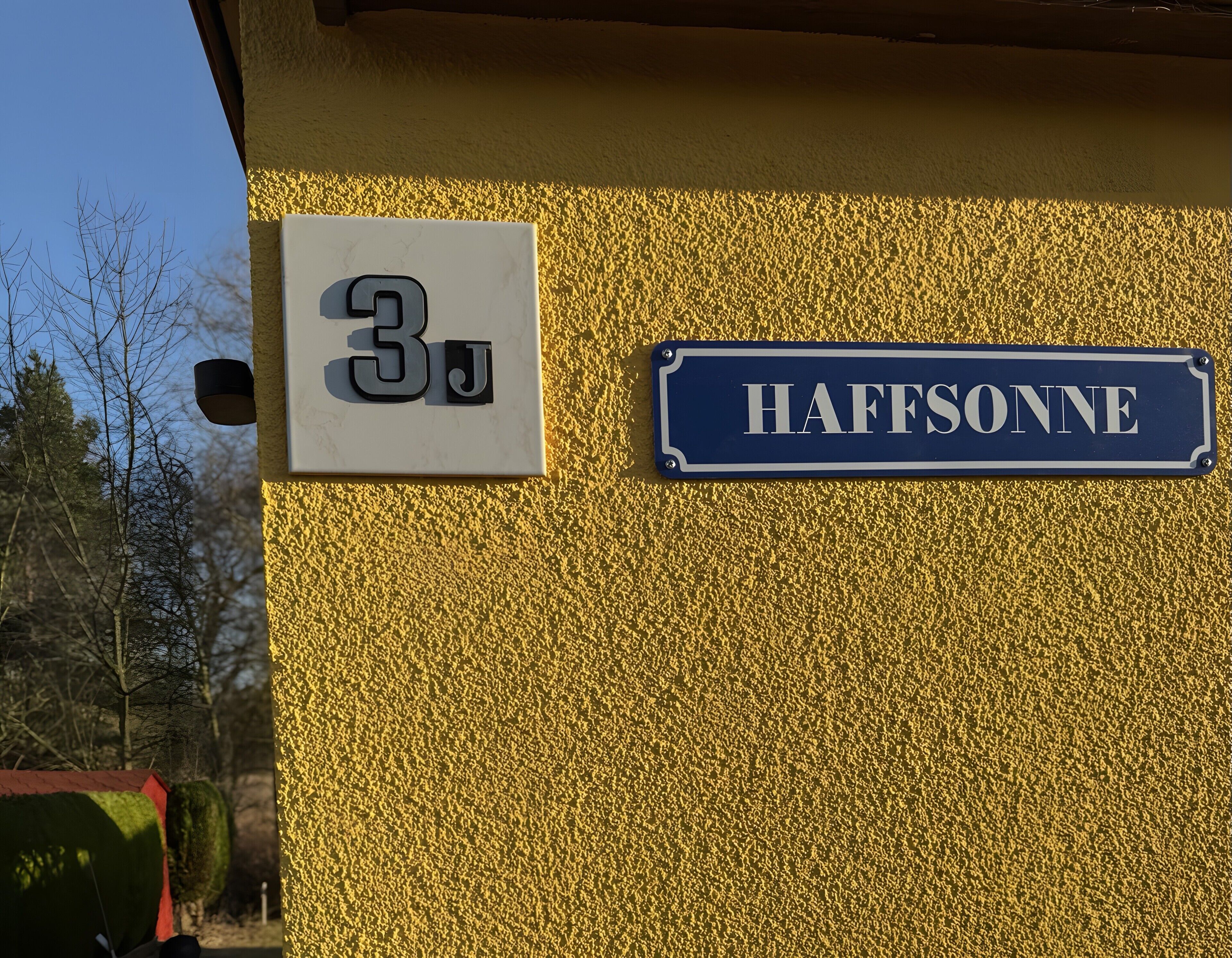 A building with a sign indicating '3J' and 'HAFFSONNE' on the wall.