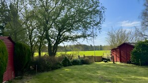 Un paysage rural avec un grand arbre, une grange rouge et un champ verdoyant.