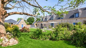 A stone building with a large tree in the foreground, a well-maintained lawn, and a clear sky. - Charming villa with heated pool • Sainte-Marine - Village and beaches on foot (Combrit)