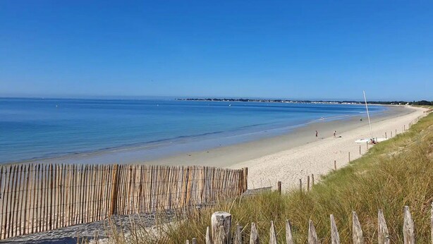 A beach with a wooden fence, sandy shore, and calm sea. - Charming villa with heated pool • Sainte-Marine - Village and beaches on foot (Combrit)