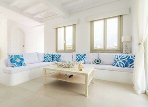 Una sala de estar blanca con un sofá, una mesa de centro y dos ventanas.