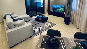 Un salon moderne comprenant un canapé, une table basse, un téléviseur et un coin repas aménagé avec une table et des chaises.