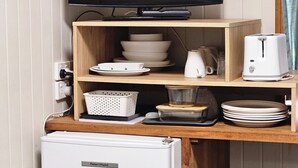 Eine Küchenzeile mit Fernseher, Regalen mit Geschirr, einem Toaster und einem Kühlschrank.