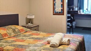 Ein Hotelzimmer mit Bett, Schreibtisch, Stuhl und einem Bild an der Wand.