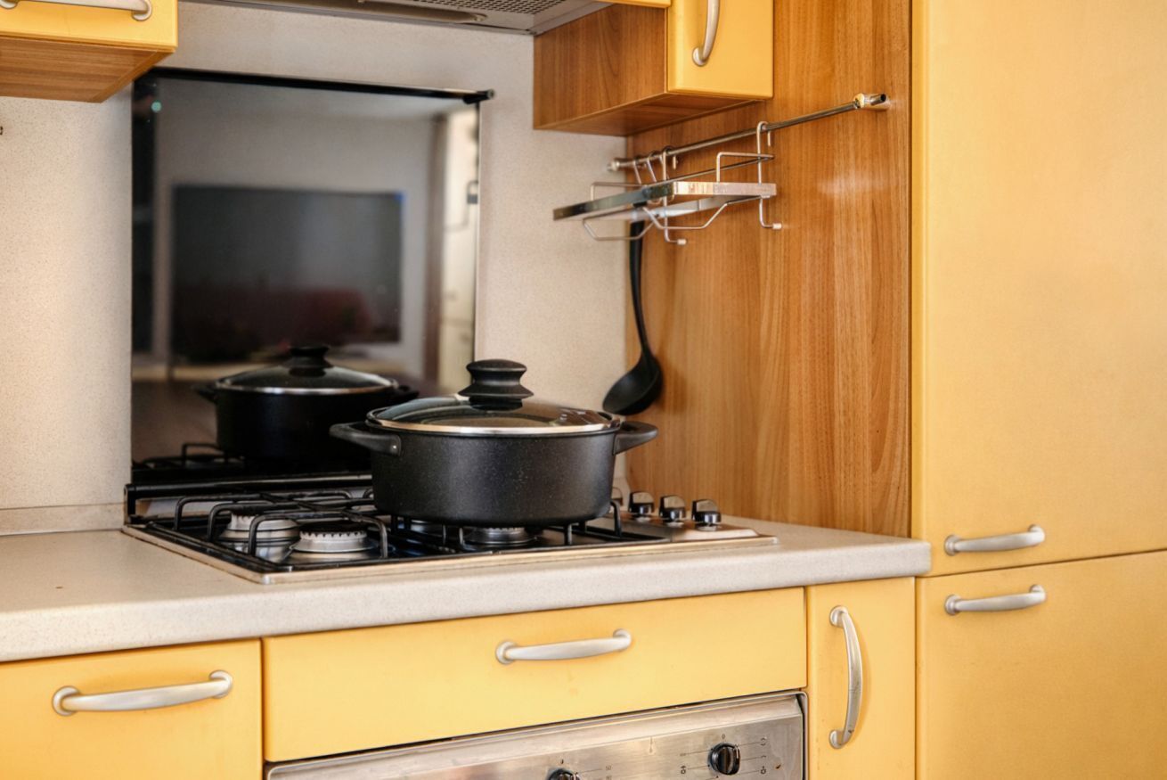 A kitchen with a stove, pots, and wooden cabinets.