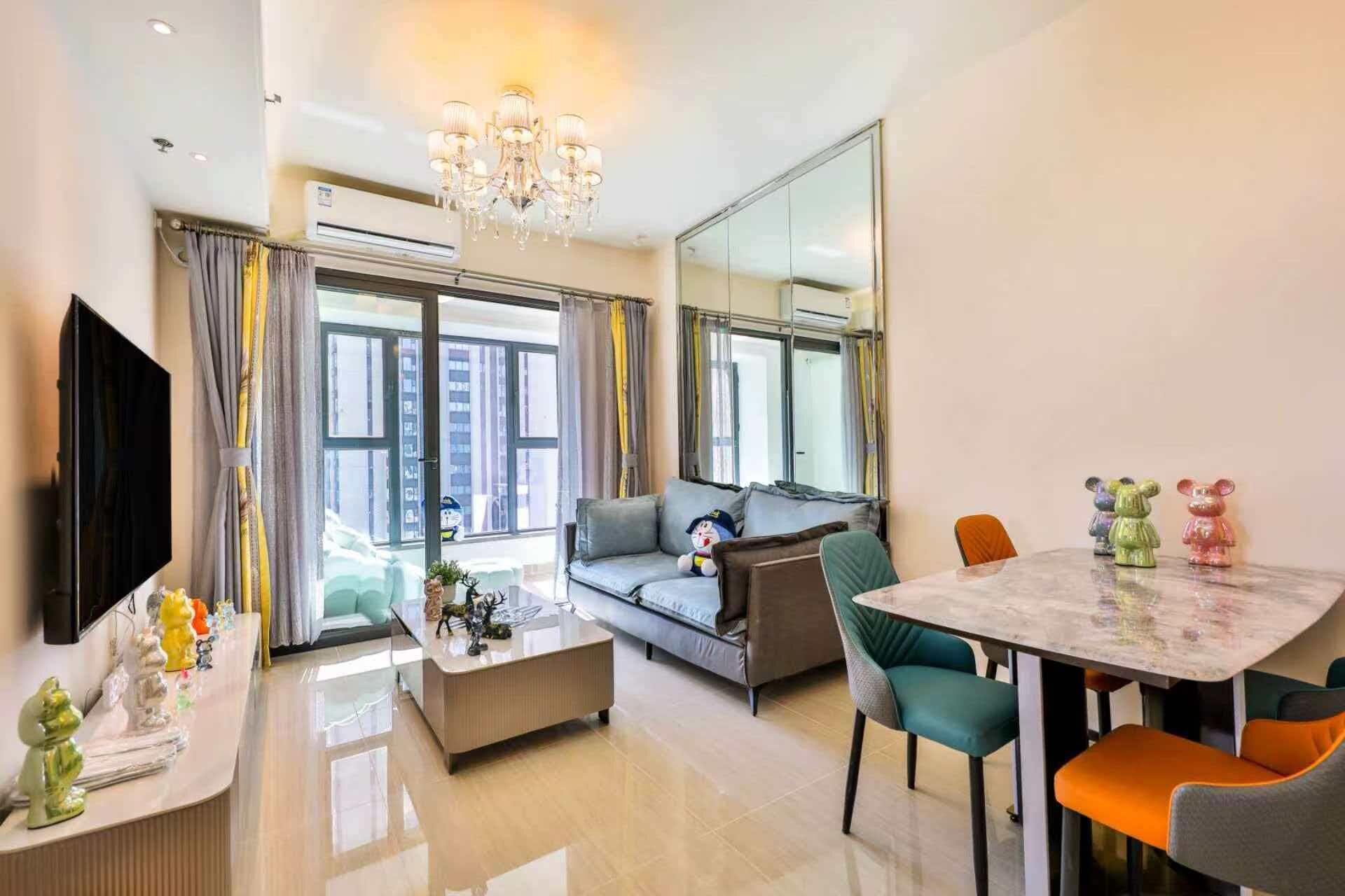 A modern living room with a sofa, a coffee table, a TV, and a dining area with chairs and a table.