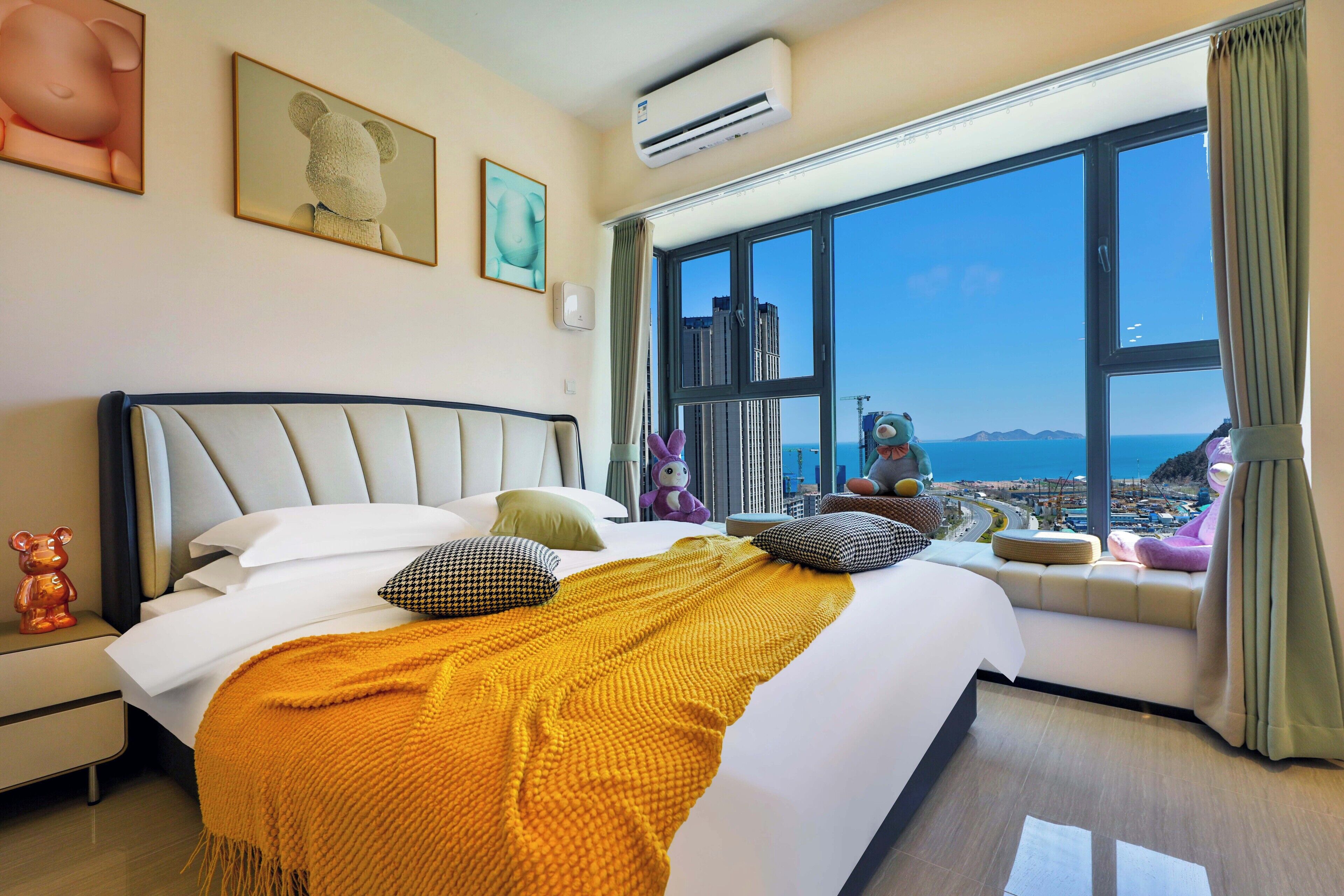 A hotel room with a large bed, a view of the sea, and a window with a view of the city.