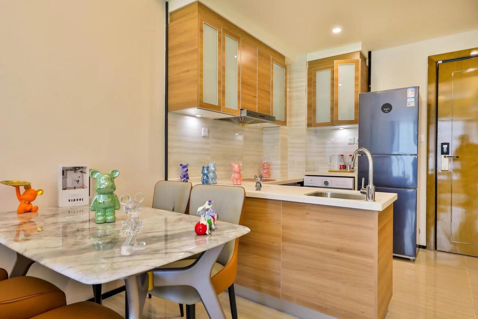 A modern kitchen with wooden cabinets, a marble countertop, and a built-in refrigerator.