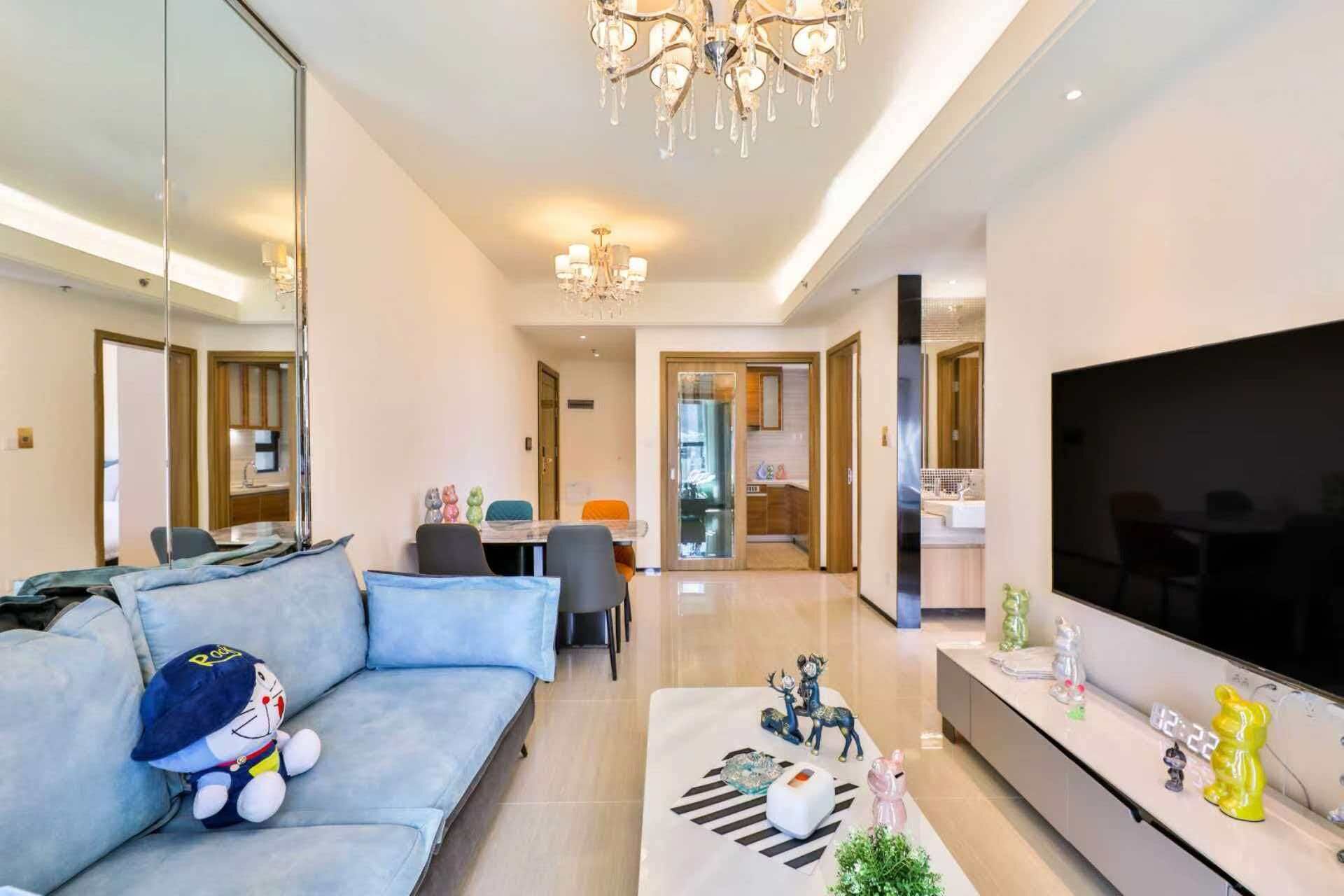 Ein modernes Wohnzimmer mit einer Couch, einem Fernseher und einer Chandelüster.