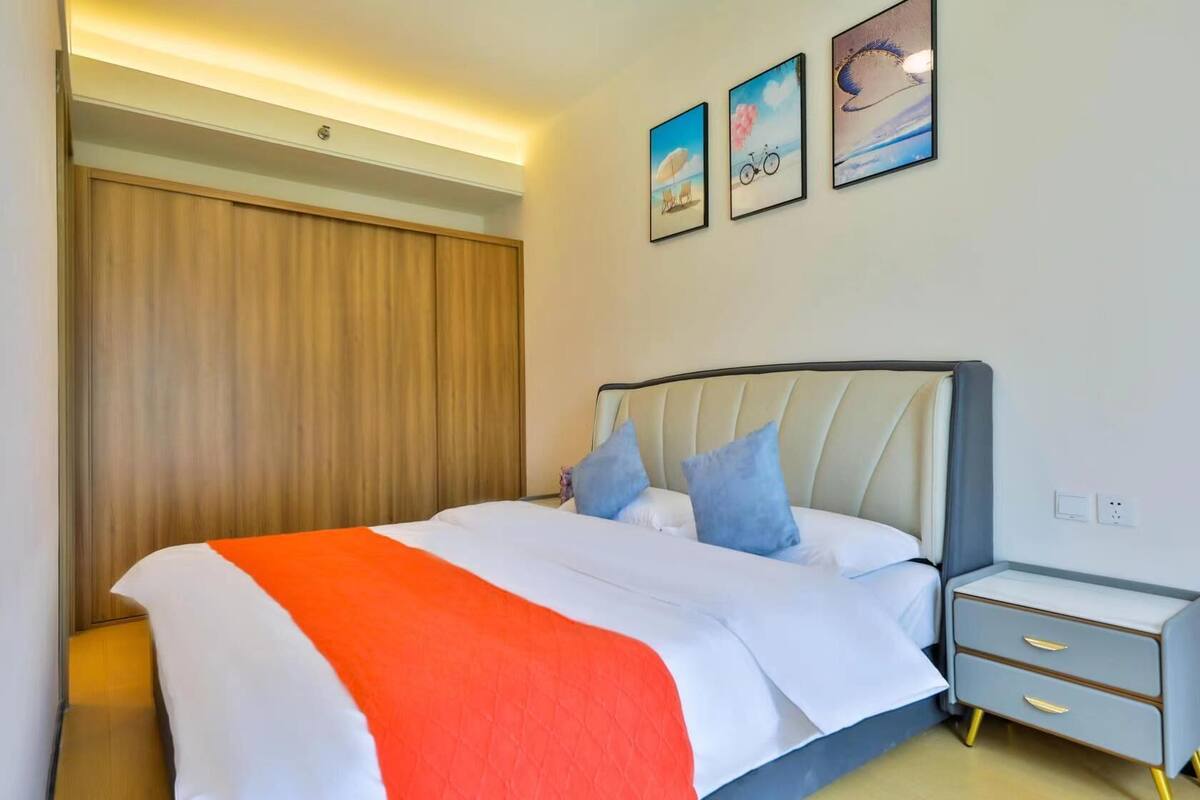 Ein Schlafzimmer mit einem Bett, Nachttischen, einem Holzschrank und drei gerahmten Bildern an der Wand.