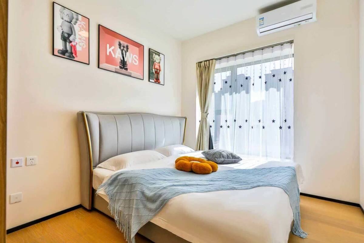 Ein ordentlich eingerichtetes Schlafzimmer mit einem Bett, einem Fenster mit Sternenmuster-Vorhängen und drei gerahmten Bildern an der Wand.