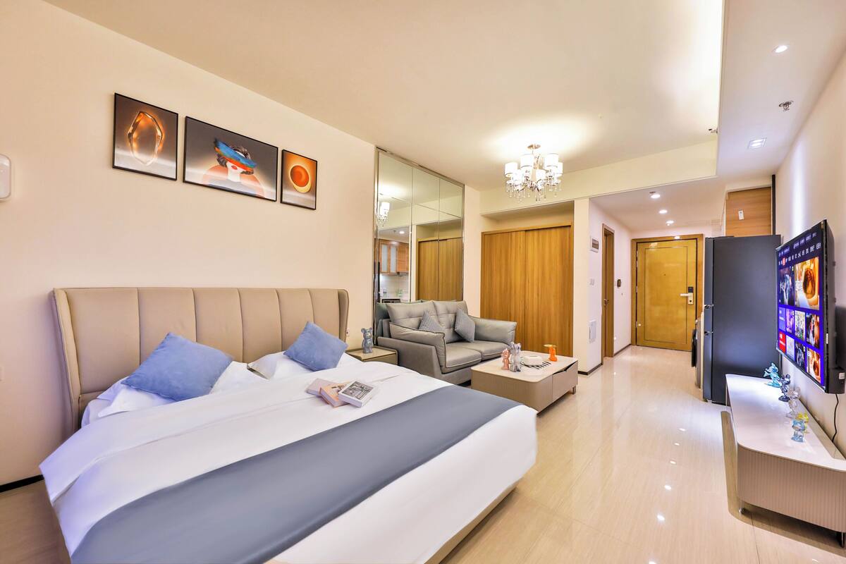 Ein Hotelzimmer mit einem großen Bett, einer Couch, einem Fernseher und einem Schreibtisch.