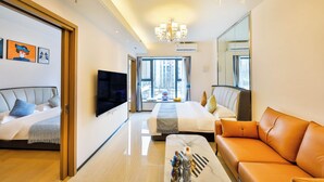 Una habitación de hotel moderna con una cama grande, un sofá, un televisor y una araña.