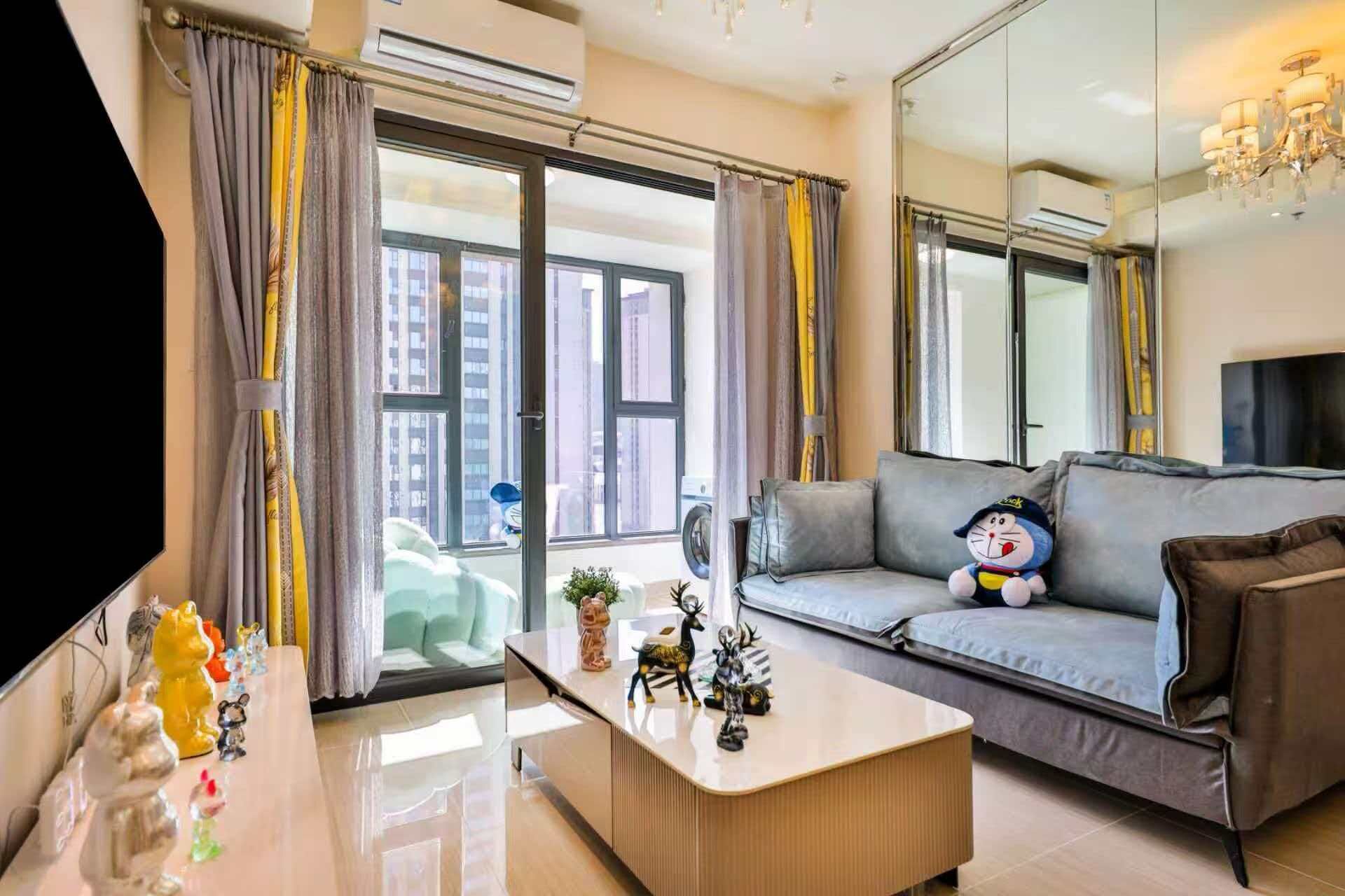 A modern living room with a grey sofa, a coffee table, and a plush toy.