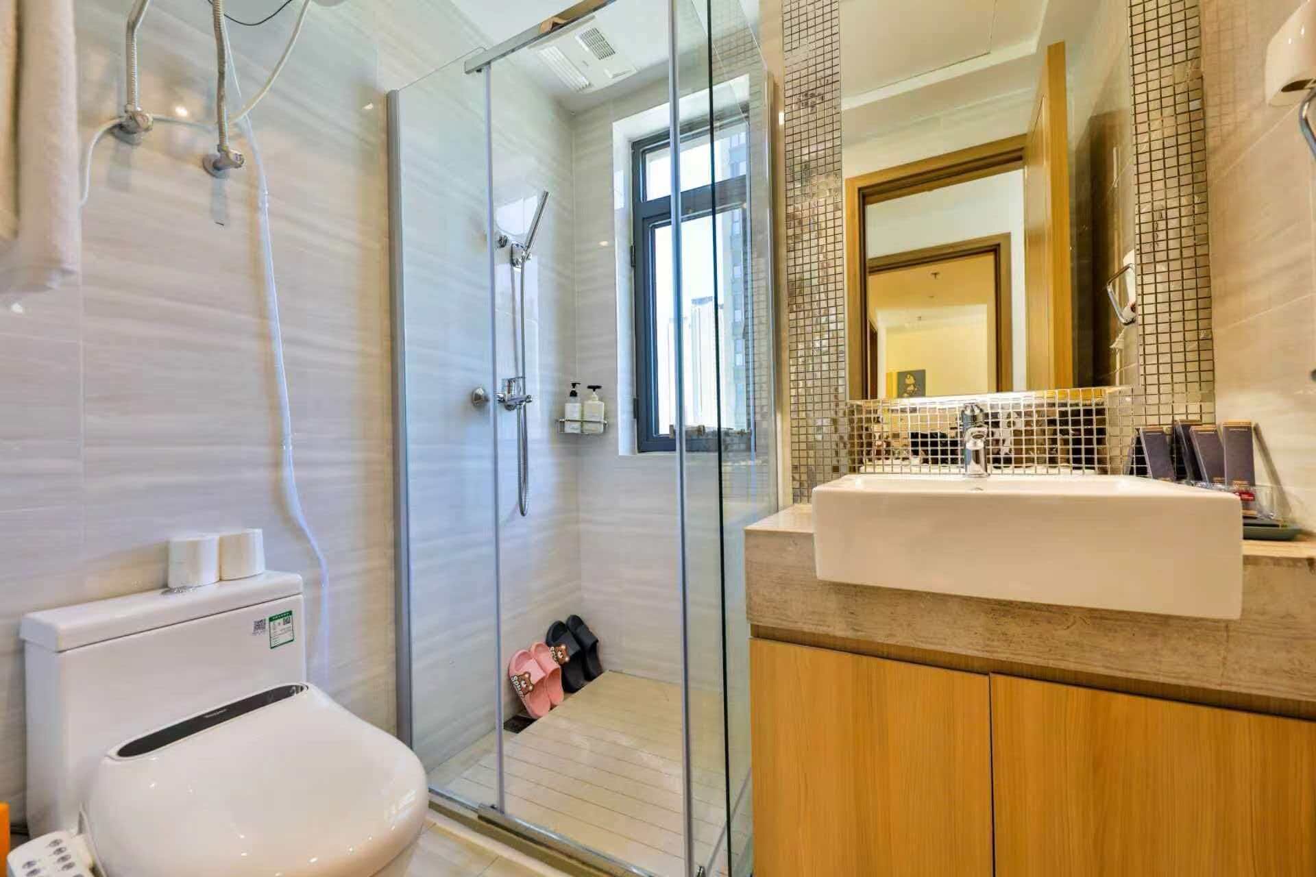 A modern bathroom with a glass shower enclosure, a white sink, and a wooden vanity.