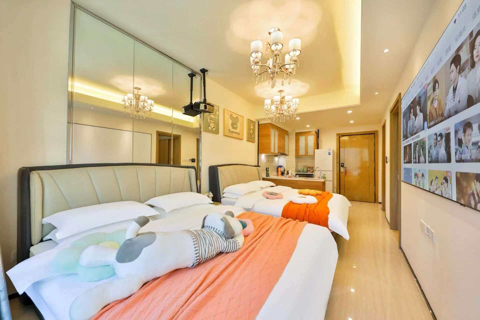 A hotel room with two beds, a chandelier, a large mirror, and a wall with pictures.