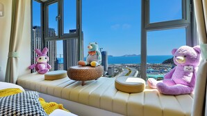 Asiento junto a la ventana con juguetes suaves y vista a una ciudad costera.