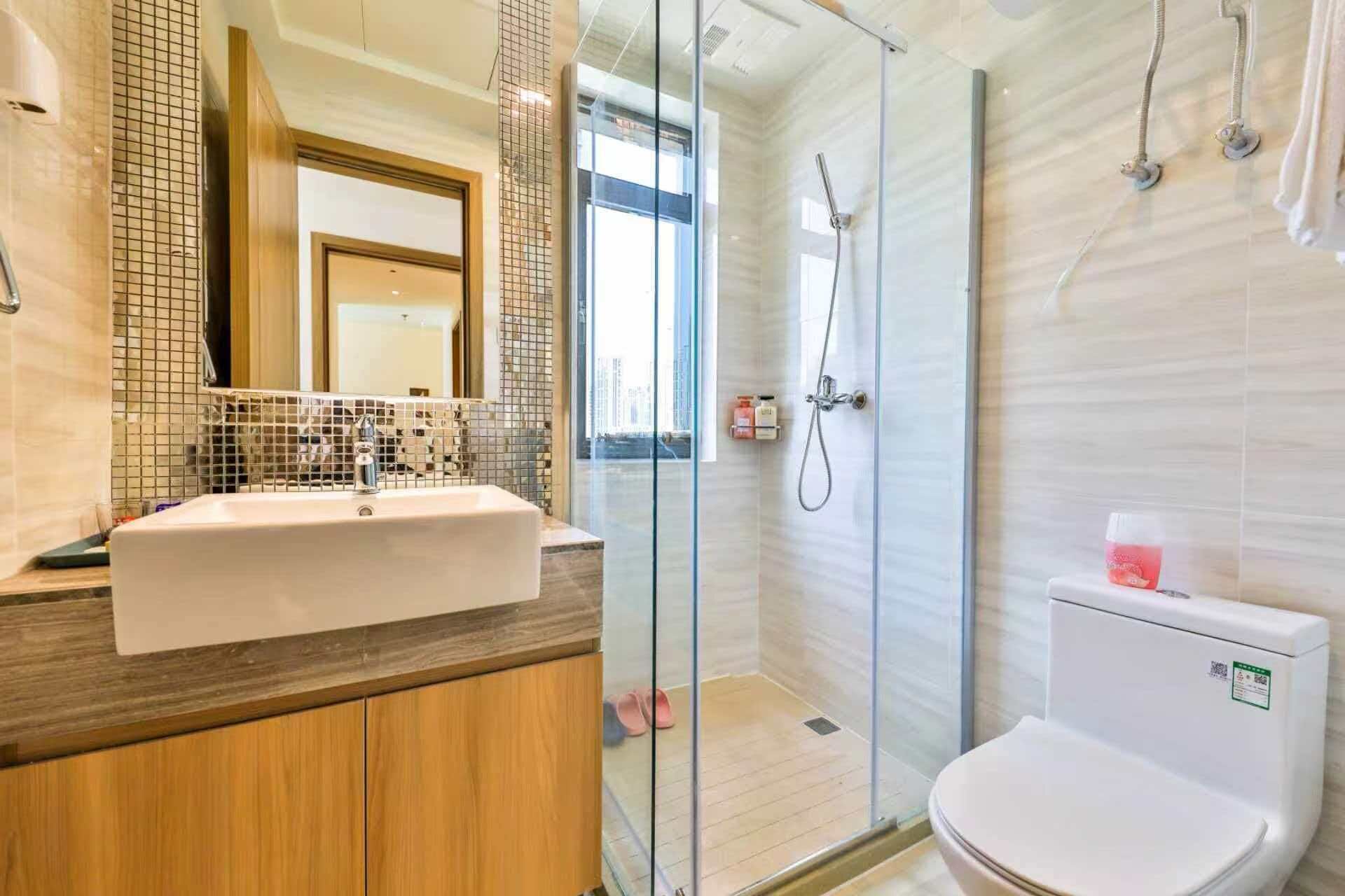 A bathroom with a glass shower enclosure, a white sink, and a toilet.