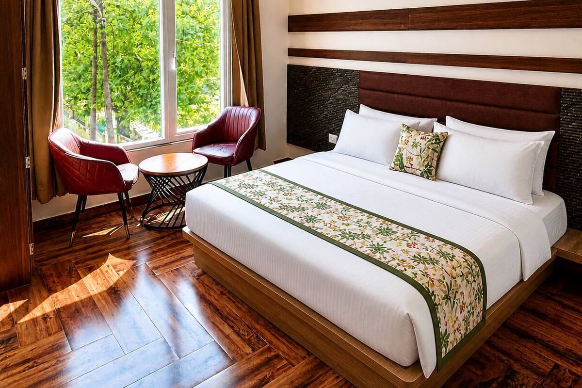 A hotel room with a large bed, a desk, a chair, and a window with curtains.