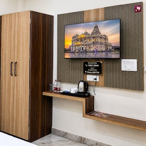 A reception desk with a framed picture of a temple, a wooden cabinet, and a sign with contact information. - The Manthan Heights (Vrindavan)