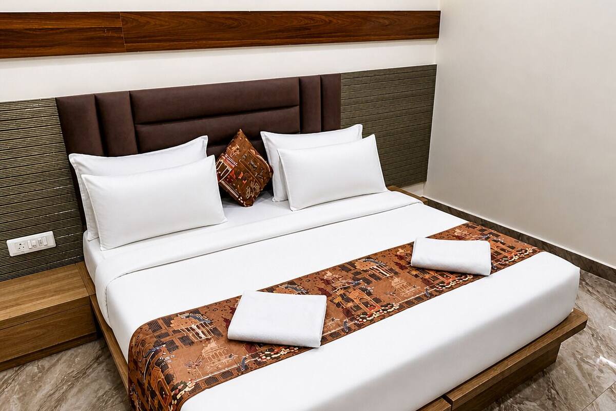 A bed with white bedding, a brown headboard, and a patterned throw blanket.
