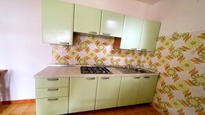 Una cocina con gabinetes verdes, una estufa a gas y un lavamanos.
