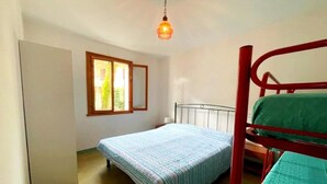 Un alojamiento pequeño y de una sola habitación, con cama, ventana y lámpara colgante.