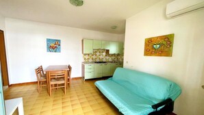 Un espacio habitable compacto con comedor, kitchenette y sofá.