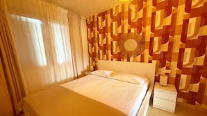 Ein Hotelzimmer mit einem Bett, Vorhängen, einem Nachttisch und einer Wand mit Muster.