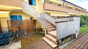 Ein mehrstöckiges Gebäude mit einer Treppe, die zu den oberen Stockwerken führt, einem Holzzaun und einem Fahrrad vor der Tür.
