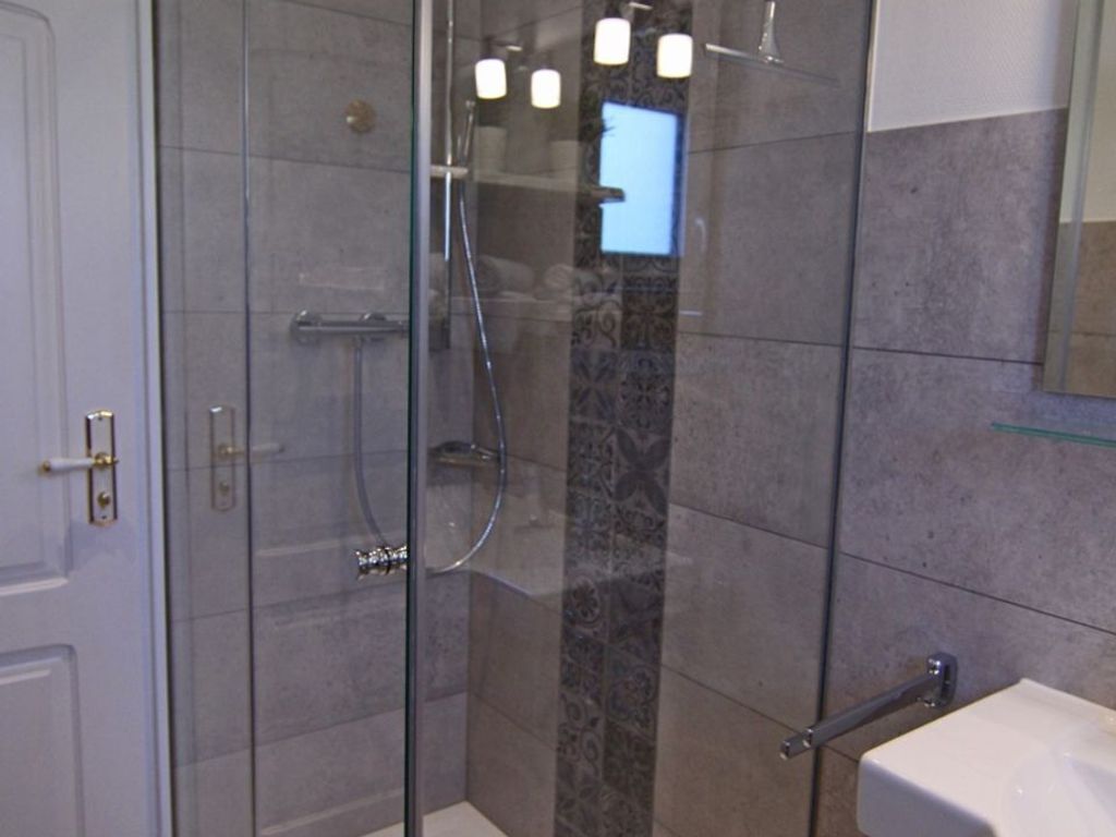 A modern bathroom with a glass-enclosed shower, a white sink, and a marble accent wall.
