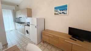 Cuina compacta amb rentadora, nevera i un armari de fusta.