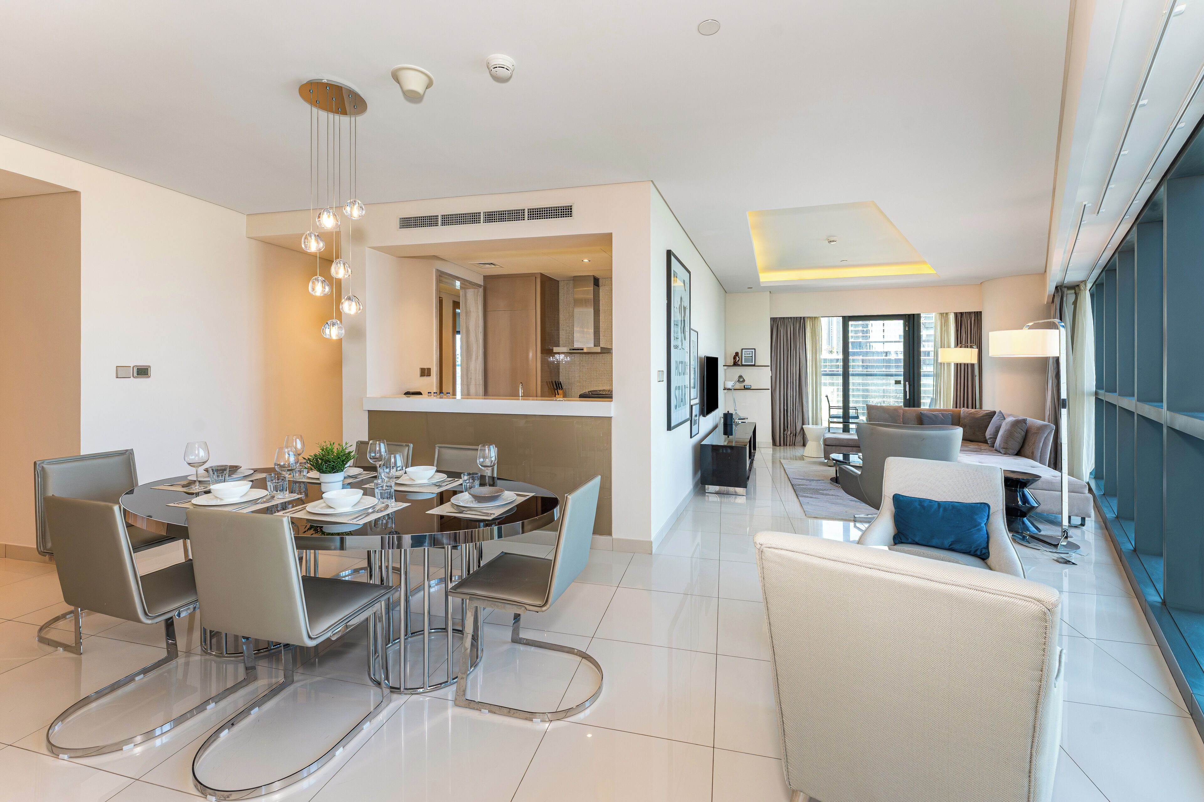 A modern hotel room with a dining area, a living area, and a view of the city.