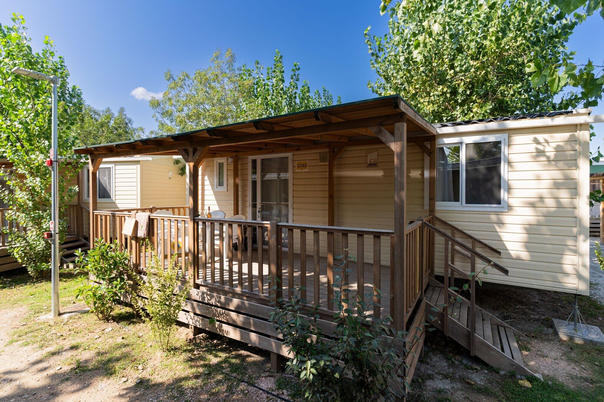 A single-story mobile home with a wooden deck and a covered porch.