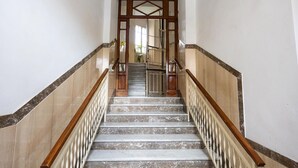 Eine Marmortreppe mit hölzernen Geländern und einem Metallgitter am oberen Ende.