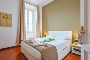 Ein Hotelzimmer mit einem Bett, einem Nachttisch, einem Fenster mit Vorhängen, einem Wandbild und einem Schild an der Tür.