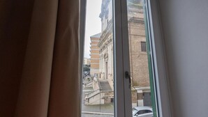 Ein Fenster mit Blick auf ein Gebäude im klassischen Stil, inklusive einer Treppe und einer Statue.