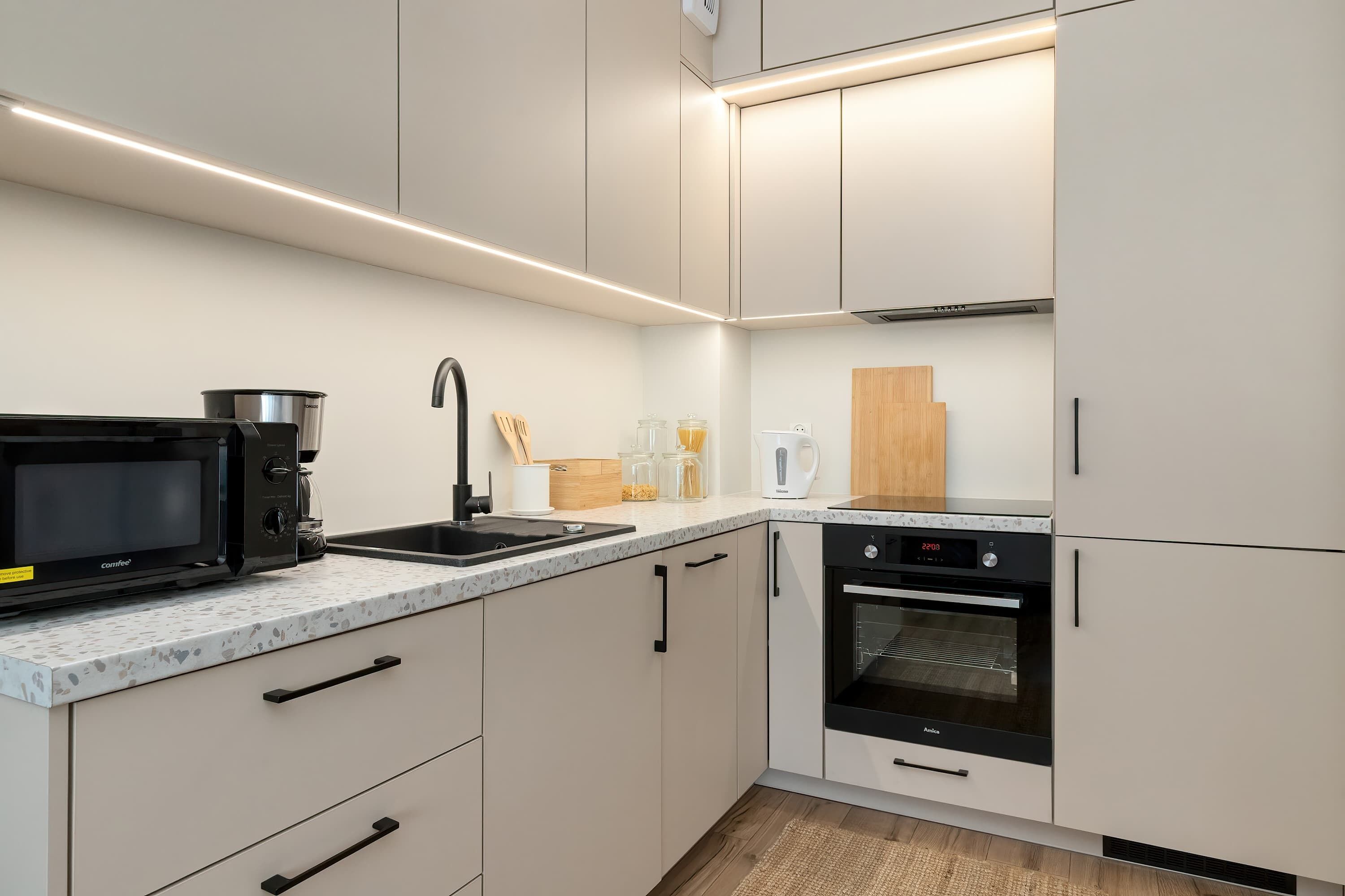 Una cocina moderna con microondas, cafetera, fregadero y horno.