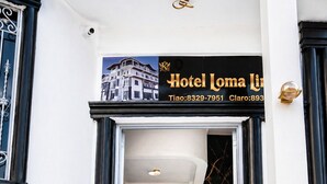 L’entrée d’un hôtel, avec un panneau indicateur, deux perroquets décoratifs et un escalier en marbre.